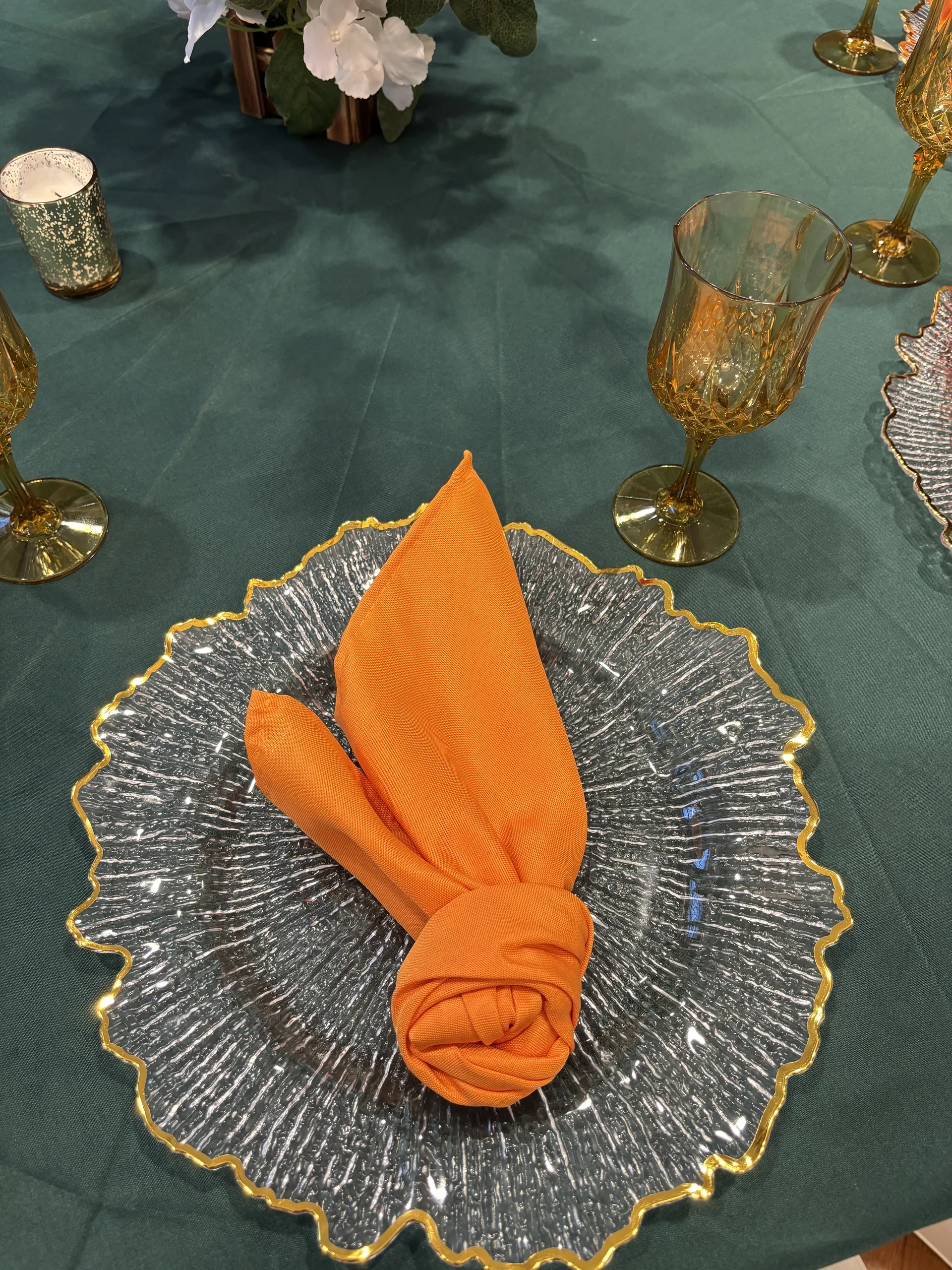 Orange napkin on clear gold-rimmed charger plate