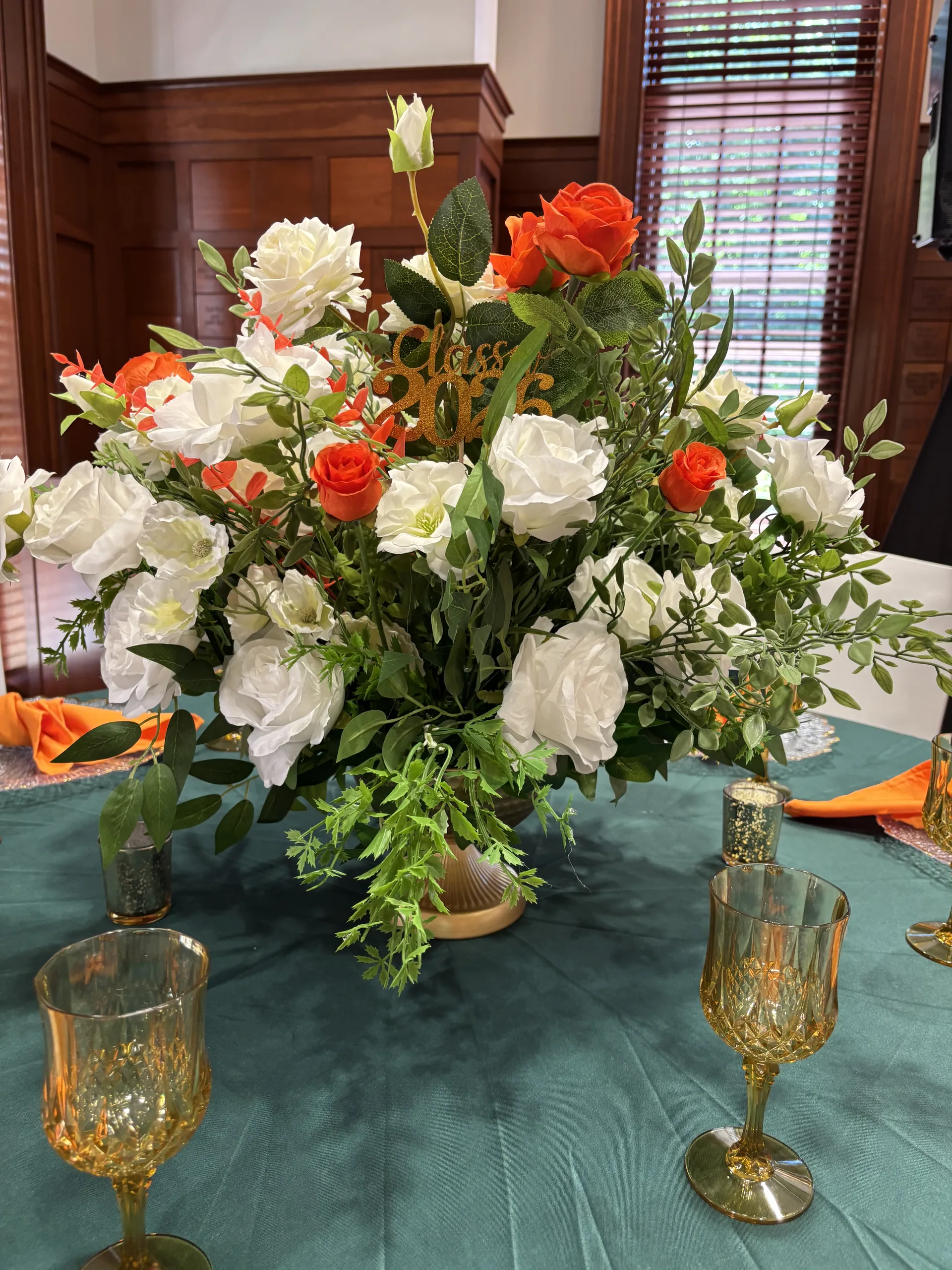 White and orange floral centerpiece on emerald tablecloth