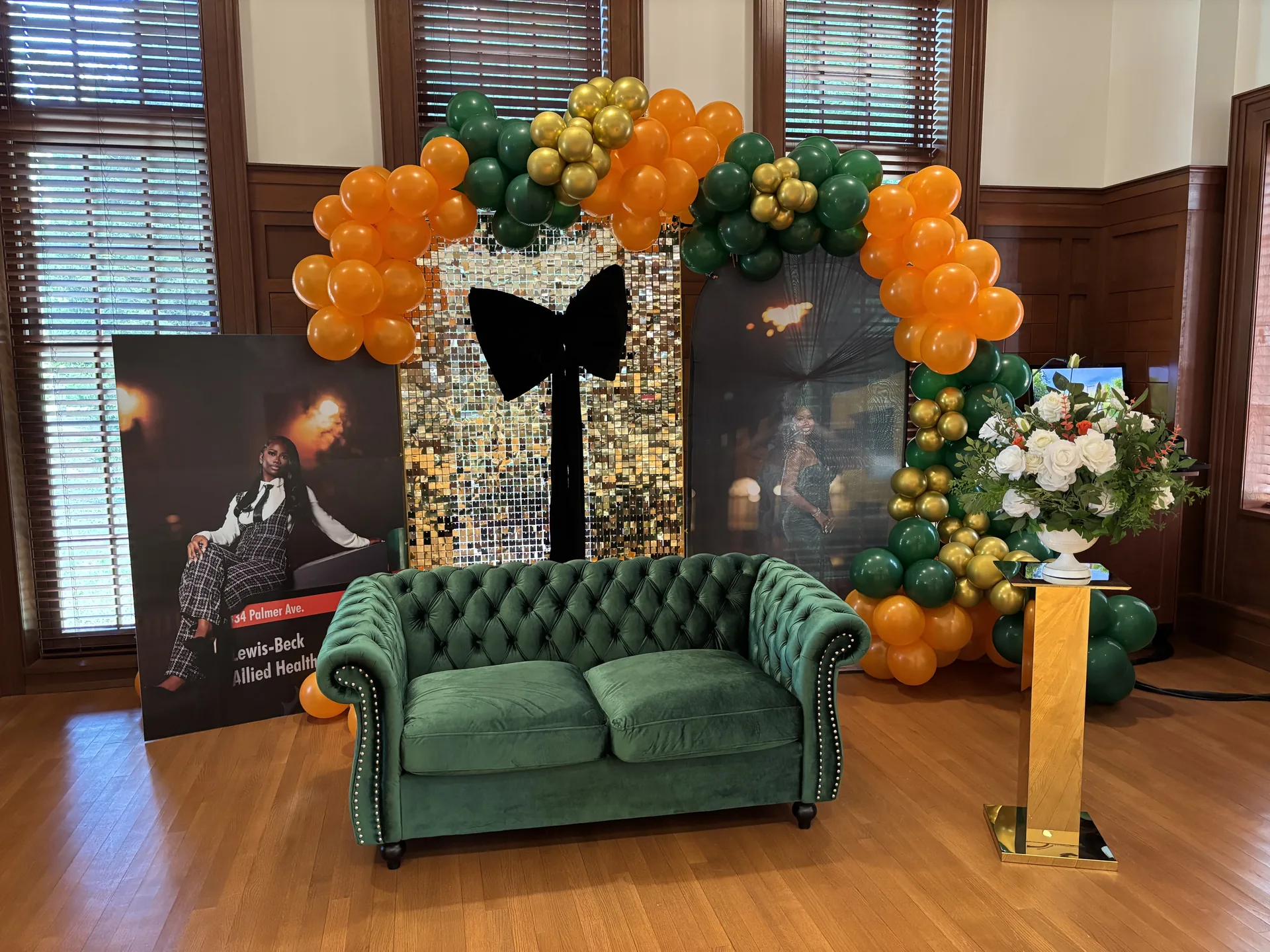 Emerald couch with orange green and gold graduation balloon backdrop