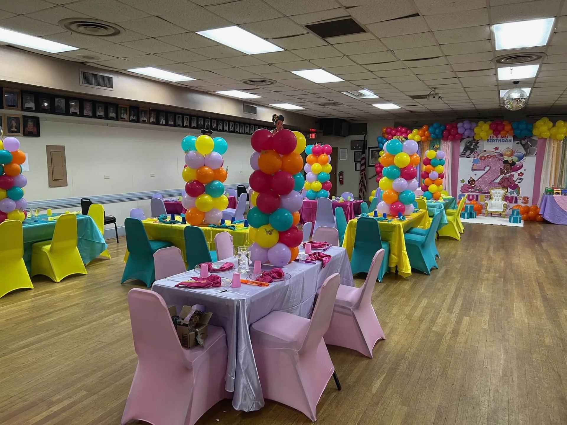 Pink children's table surrounded by bright balloon columns and themed backdrop