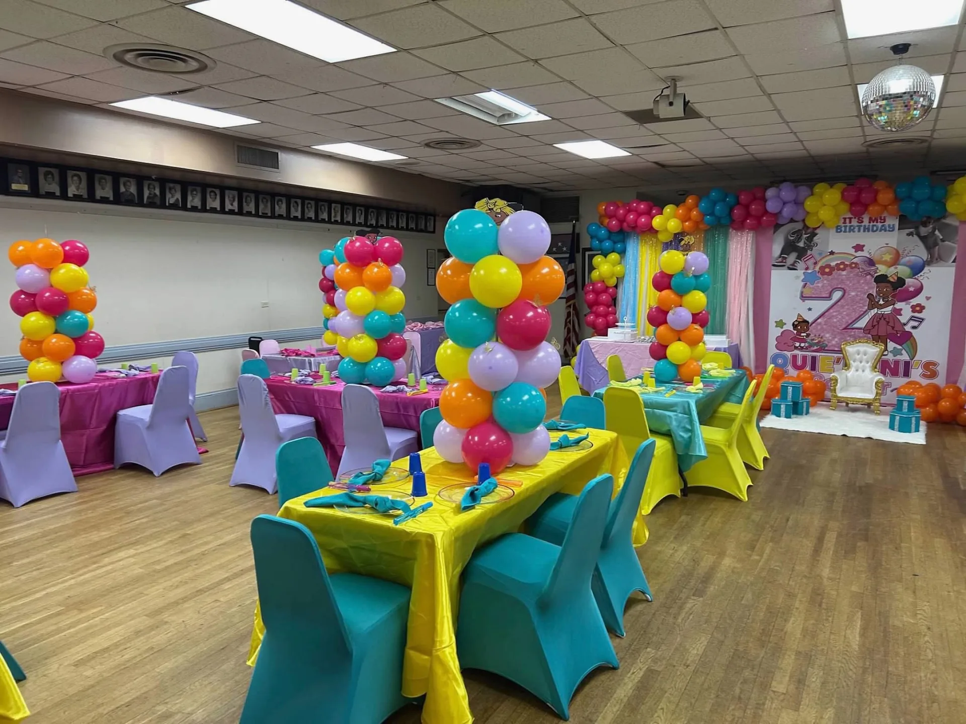 Turquoise and yellow children's tables with balloon columns and birthday backdrop