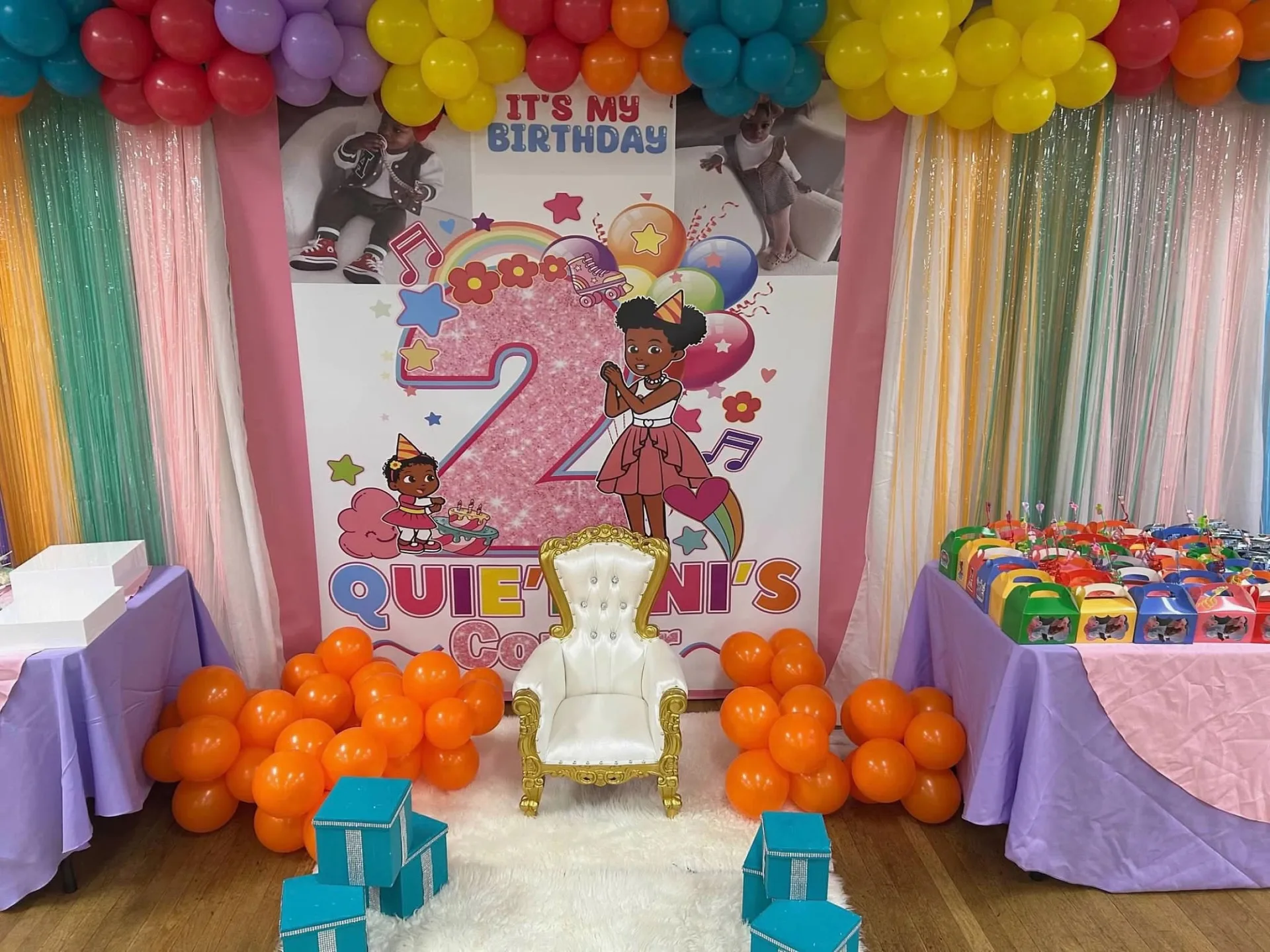 Wide custom birthday backdrop with balloon garland, throne chair, and favor tables