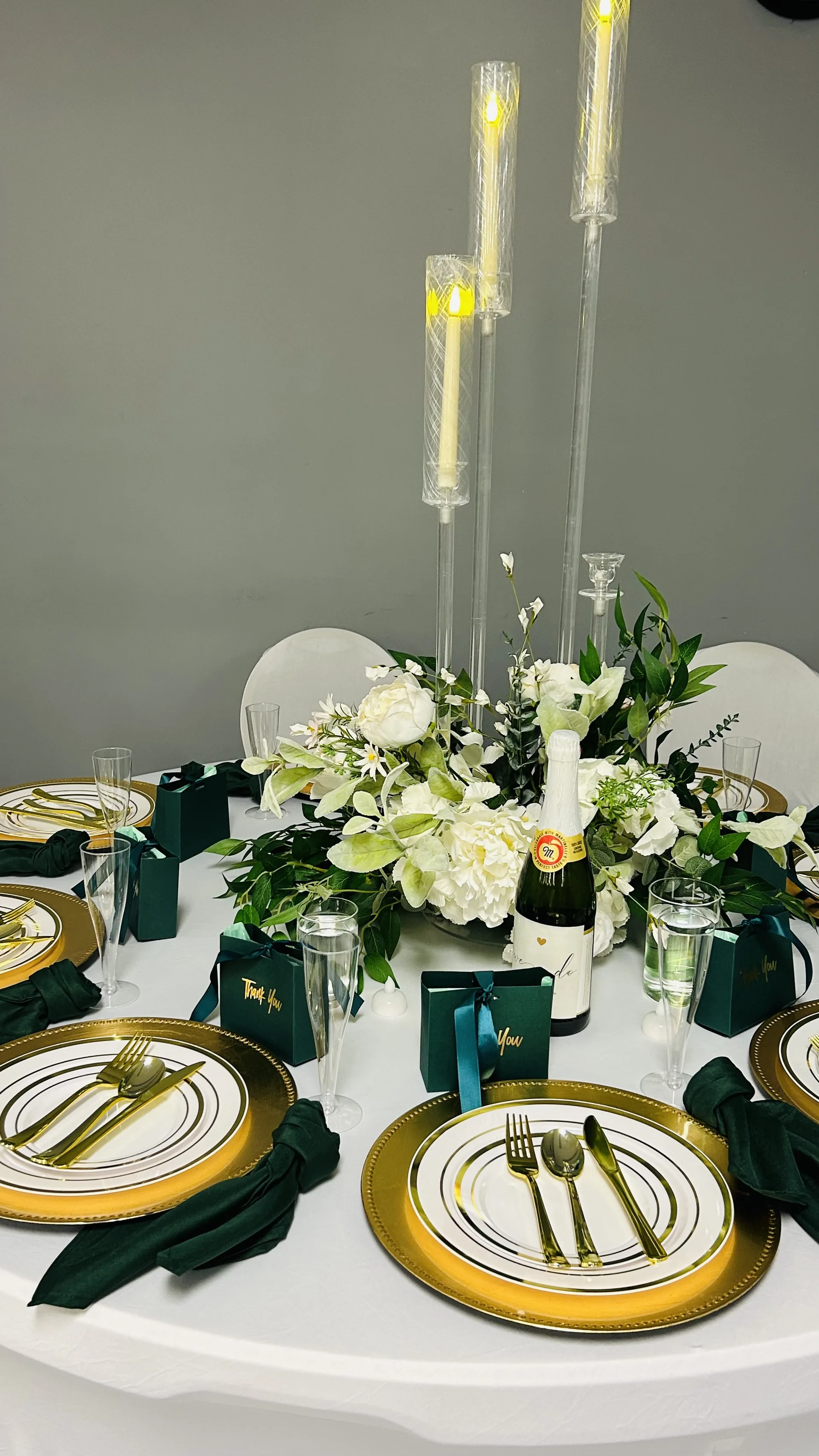 Luxury white and emerald dinner table styling with gold charger plates and candlelight