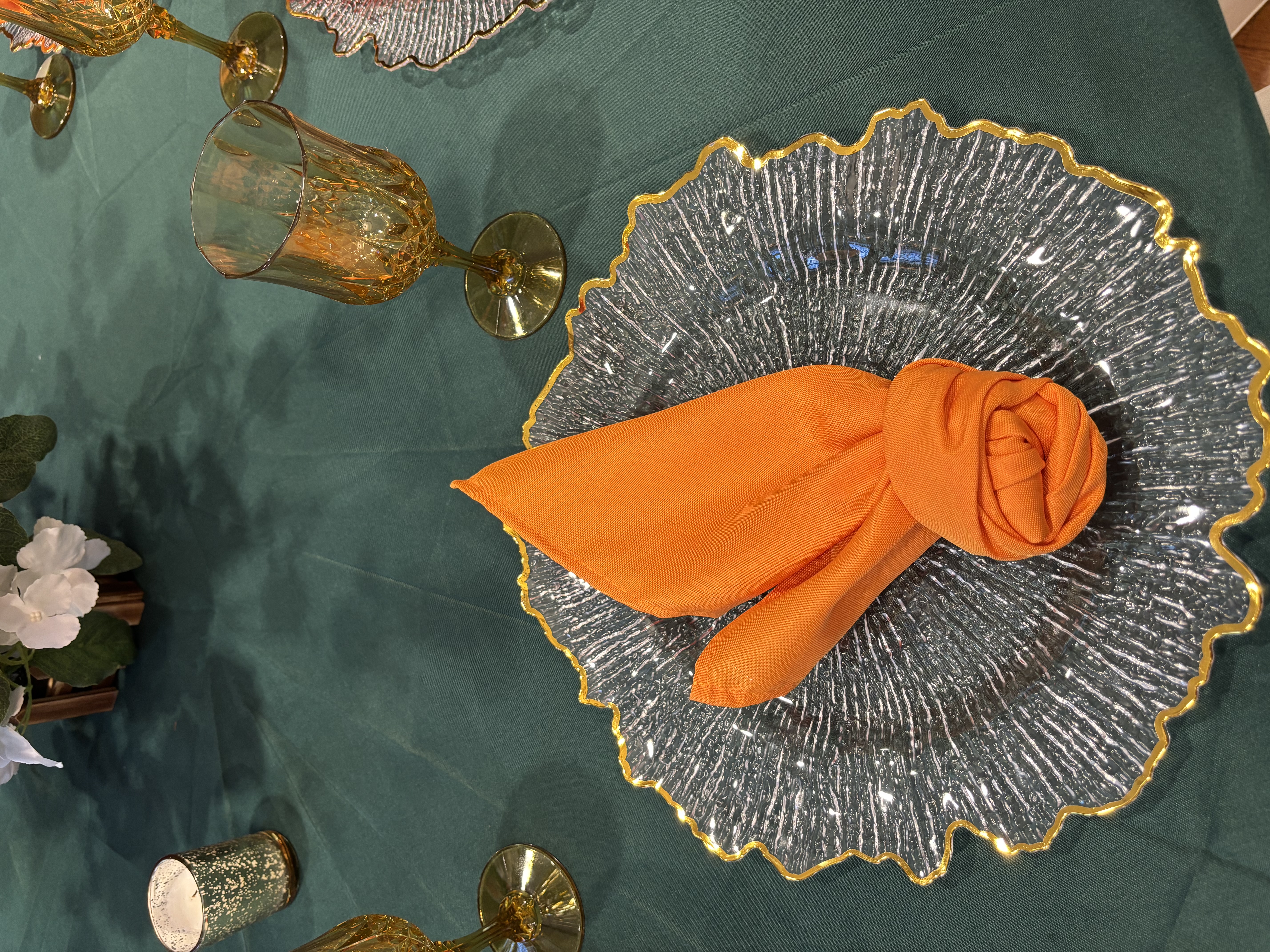 Orange napkin on clear gold-rimmed charger plate