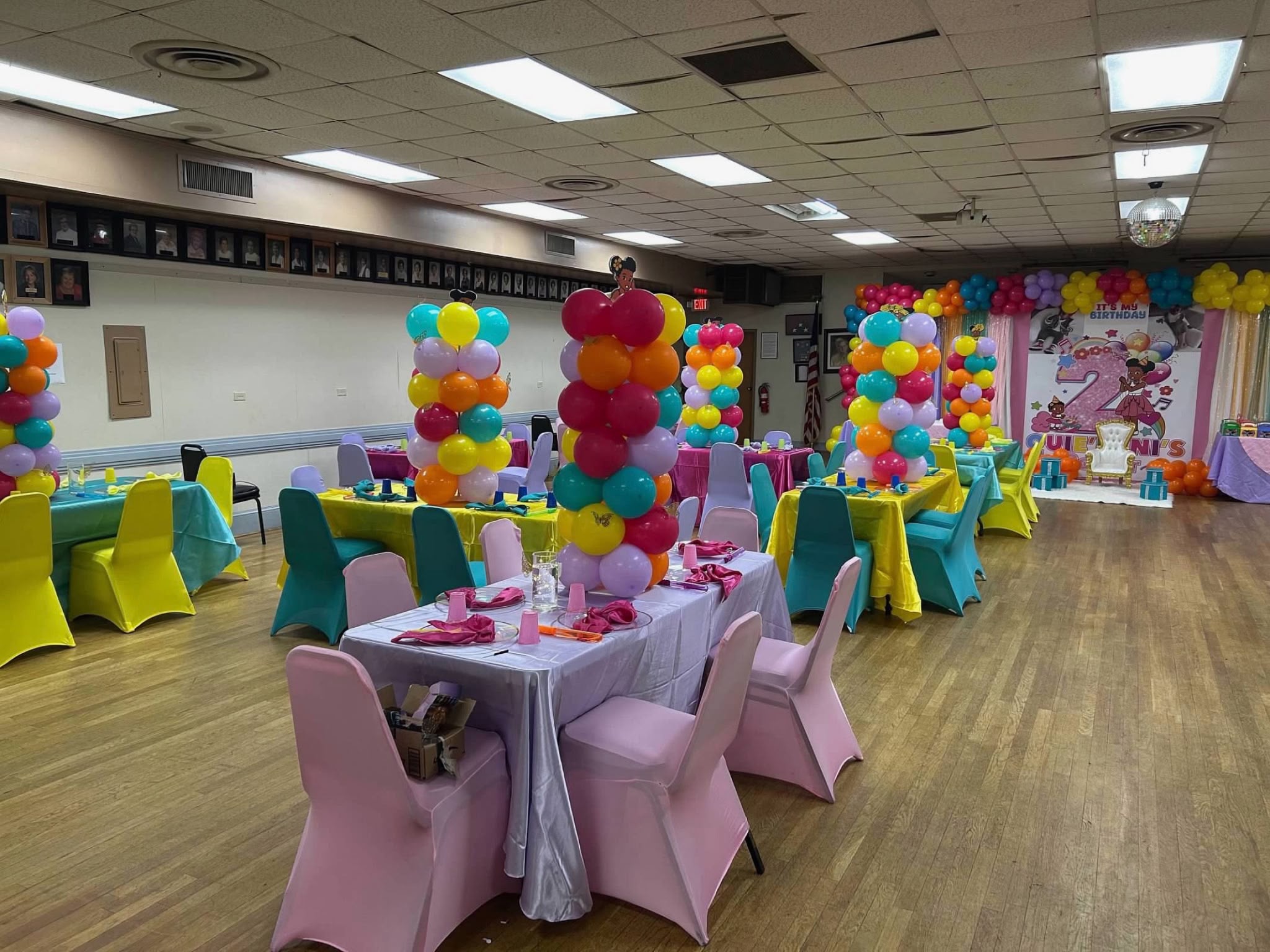 Pink children's table surrounded by bright balloon columns and themed backdrop
