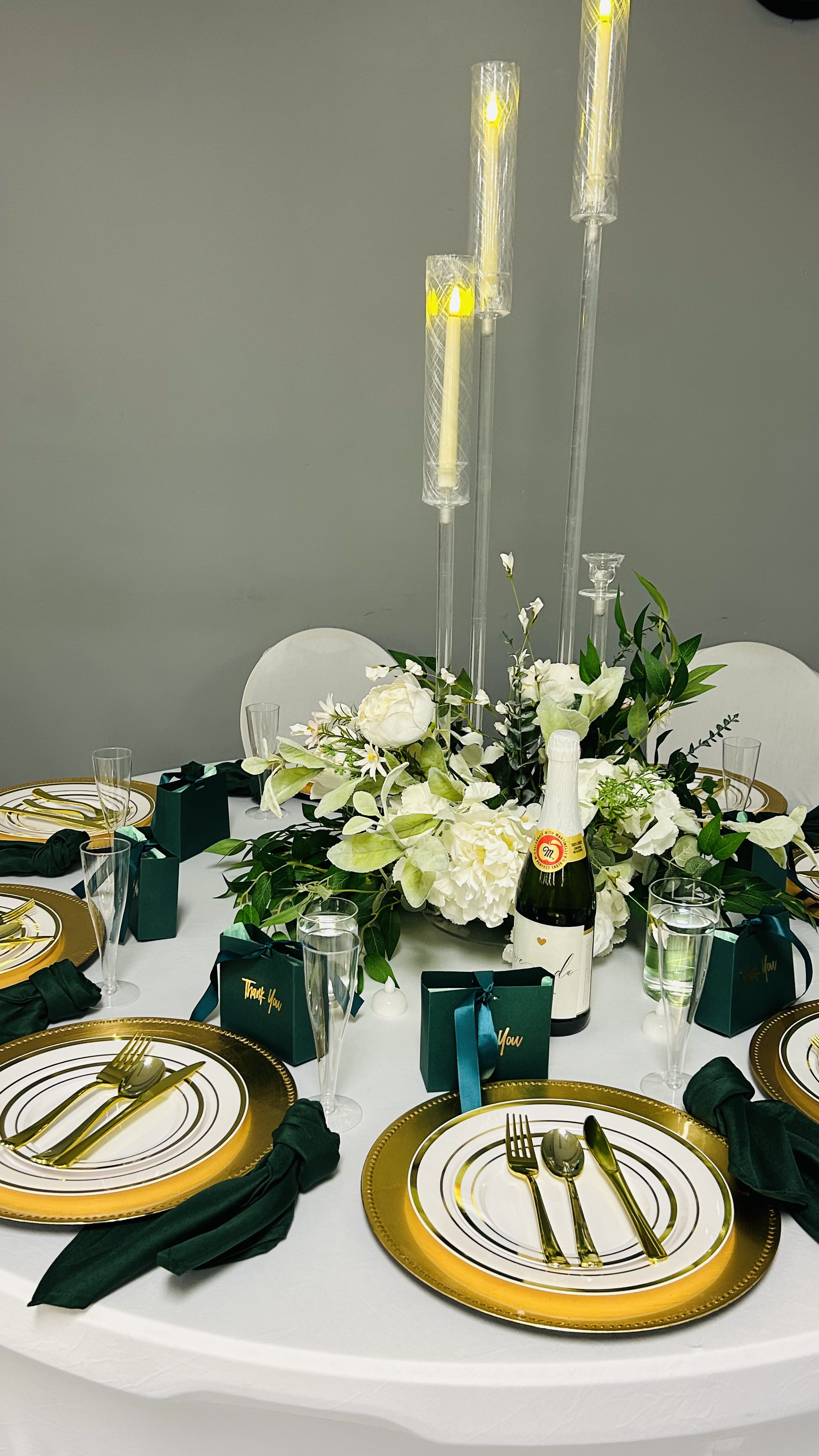 Luxury white and emerald dinner table styling with gold charger plates and candlelight